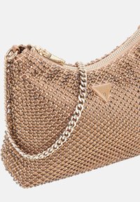 Beige sequined clutch bag met kettingriem, voorzien van een ritssluiting en metallic logo accent. Gestructureerde oppervlakte met ronde versieringen.