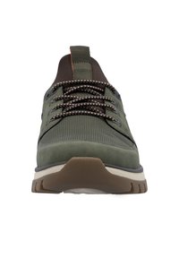 Gröna sportskor med textilstruktur och slät mocka. Har bruna accenter, prickiga snören och en vit sula med ett robust mönster.