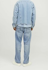 Ljust blå denimjacka med avslappnad passform och matchande ljusblå jeans. Har dubbelsömmar och klassiska bakfickor.