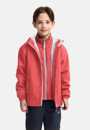 Veste imperméable corail avec une capuche et des accents gris, superposée à une veste intérieure matelassée rose clair, portée avec un pantalon sombre.