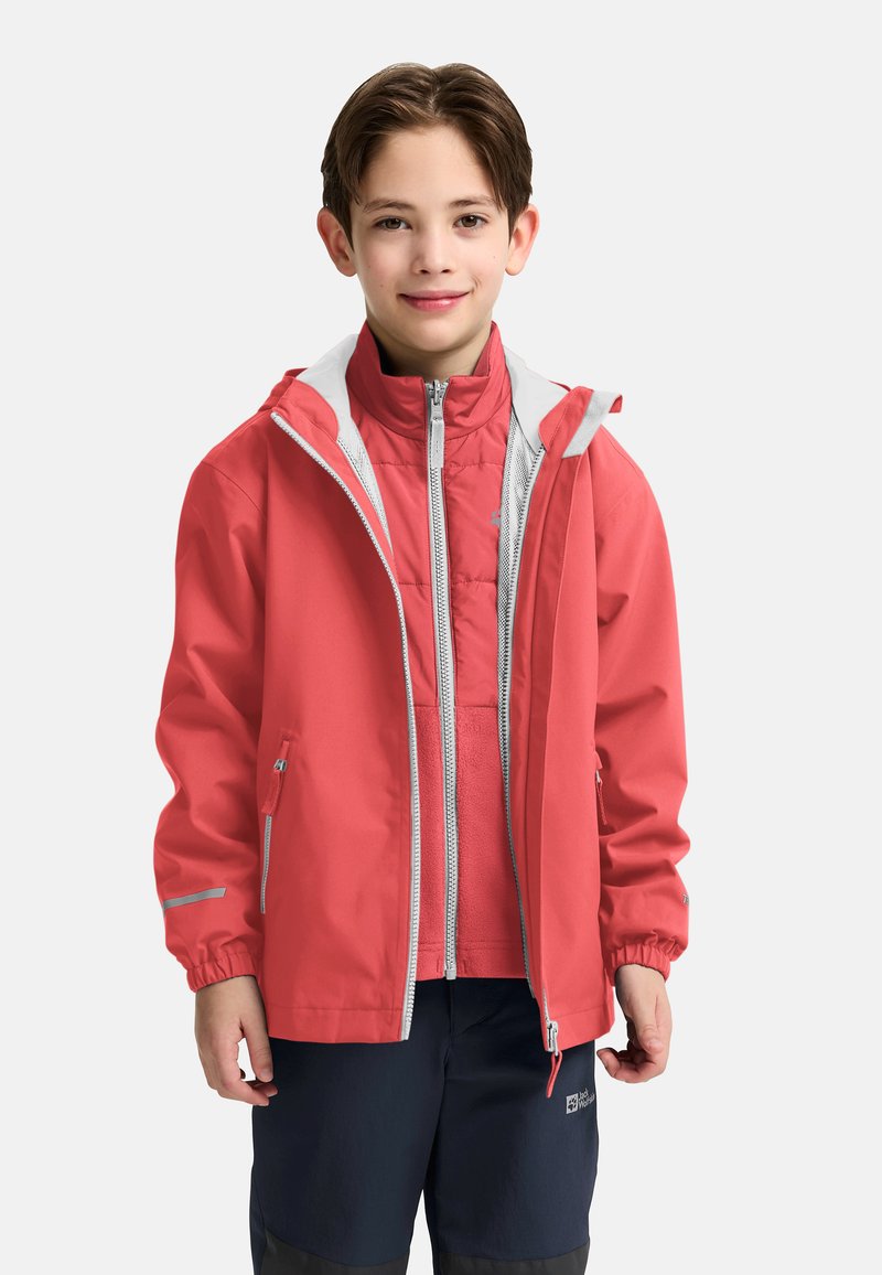 Giacca impermeabile corallo con cappuccio e accenti grigi, sovrapposta a una giacca interna trapuntata di colore rosa chiaro, indossata con pantaloni scuri.