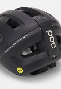 Casco da ciclismo nero con design ventilato, etichetta MIPS gialla e marchio argentato che riporta "POC". Presenta cinturini regolabili e dettagli moldati.