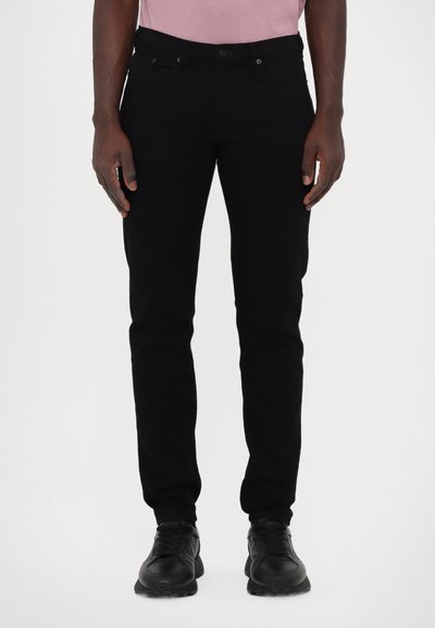 Jeans negre din denim, cu o croială slim, design cu cinci buzunare și elemente metalice la talie. Combinate cu adidași negri.