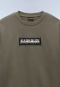 Olijfgroen sweatshirt van zachte stof. Bevat een zwart rechthoekig logo-patch met witte tekst "NAPAPIJRI geographic" gecentreerd op de borst.