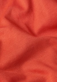 Tessuto di cotone texture in un vivace colore corallo, con superficie liscia e leggermente lucida e con sottili motivi a trama diagonale.