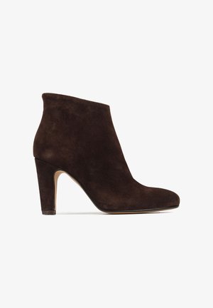 Brązowy zamszowy botek za kostkę z wąskim noskiem i obcasem w szpilce. Gładka faktura, minimalistyczny design i klasyczny fason.