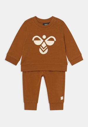 Brauner Baumwoll-Zweiteiler, bestehend aus einem langärmligen Oberteil mit einem weißen grafischen Design und passenden Hosen mit gerippten Bündchen.