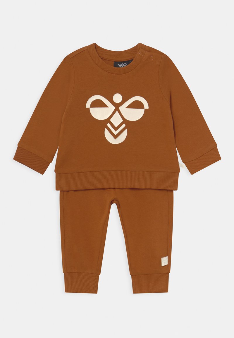 Brązowy bawełniany dwuczęściowy zestaw, składający się z długiego rękawa topu z białym graficznym wzorem oraz dopasowanych spodni z prążkowanymi mankietami.