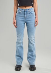 Hellblaue Jeans mit einem ausgestellten Bein-Design, aus Denim gefertigt, mit frontalen Taschen, einer hohen Taille und einem subtilen Verblassungseffekt.