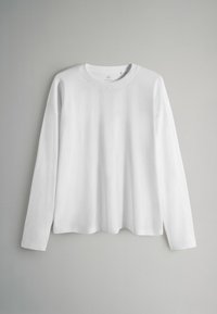 Balta garām piedurknēm T-krekls no mīksta kokvilnas. Ar apaļu izgriezumu, nolaistām plecu līnijām un vaļēju piegriezumu. Gluda tekstūra, bez rakstiem.