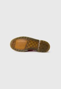 Sole of a shoe with a translucent brown rubber outsole featuring rectangular tread patterns and a distinctive crisscross design in the middle.