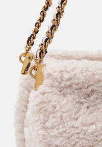 Borsa in finta pelliccia di colore rosa chiaro con una superficie texture, dotata di accessori in metallo dorato e una tracolla a catena con dettagli in pelle nera.