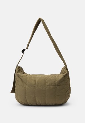 Sac à épaule matelassé vert olive avec bandoulière rembourrée réglable et fermeture éclair sur le dessus sur fond uni.