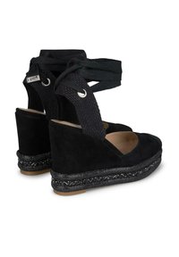 Scarpe con zeppa in suede nero con una fascia in tessuto nero testurizzato, lacci alla caviglia e un abbellimento glitterato sulla piattaforma nera.