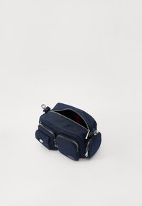 Navy-farbene Stofftasche mit mehreren Reißverschlussfächern, runder Form, silberfarbenen Beschlägen und einem roten Innenakzent. Glatte Textur.