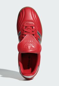 Röda lädersneakers med rund tå, texturerad ovandel och silverränder. Har en vadderad tunga med präglad logotyp och en gummisula.