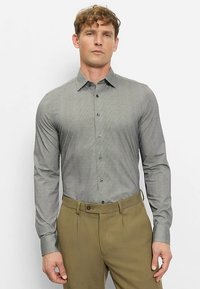 Gray button-up shirt with a subtle pattern, long sleeves, and a spread collar, paired with tailored olive green trousers.