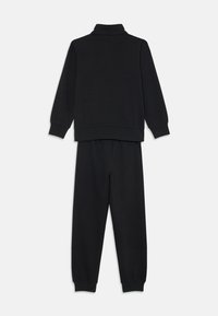 Czarny dres składający się z długiego rękawa bluzki z wysokim kołnierzem oraz pasujących spodni. Wykonany z miękkiego materiału z prążkowanymi mankietami i elastycznym pasem.