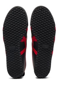 Black and red slip-on shoes with a textured rubber sole featuring a star pattern and branded label. Smooth upper material with side accents.
