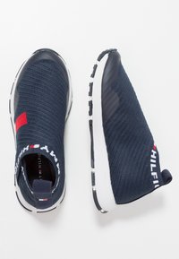 Zapatillas náuticas sin cordones con parte superior de punto texturizado, puntera de goma y suela blanca. Presenta un acento rojo, logotipo en el talón y un cuello estampado.