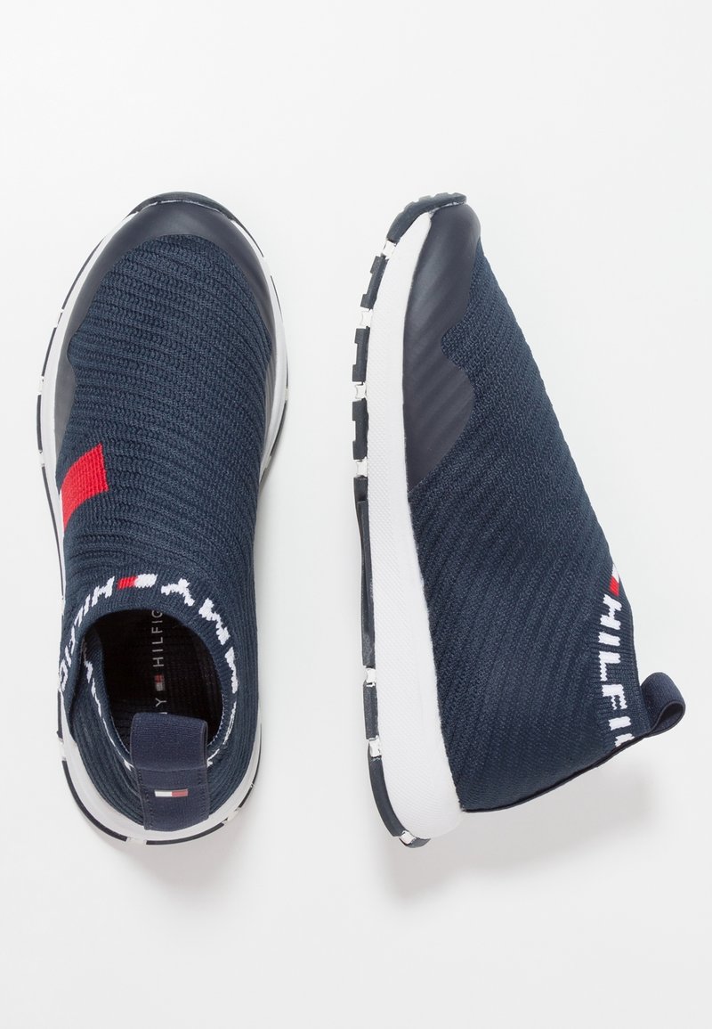 Zapatillas náuticas sin cordones con parte superior de punto texturizado, puntera de goma y suela blanca. Presenta un acento rojo, logotipo en el talón y un cuello estampado.