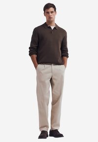 Braunes Polohemd mit langen Ärmeln, beigefarbene Hose und dunkle Schuhe. Verfügt über einen klassischen Kragen, eine lockere Passform und ein nahtloses Design mit neutralen Farben.