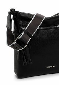 Black leather crossbody bag with textured finish, silver hardware, detachable strap featuring a brown and white stripe, and side tassel detail.