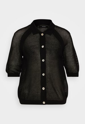 Musta verkkomallinen neuletakki, jossa on kauluspääntie, lyhyet hihat ja napitettava etuosa. Teksturoitu kangas, jossa on röyhelöitä kauluksessa ja hihansuissa.