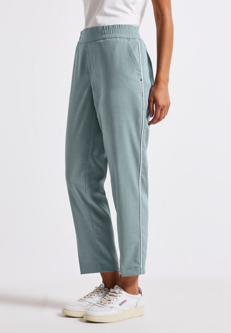 Helleblaue, taillierte Hose mit elastischem Bund und seitlichen Paspeldetails. Aus einem glatten Stoff gefertigt und mit Seitentaschen ausgestattet.