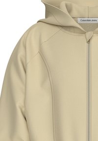 Felpa beige con zip e cappuccio, con cuciture visibili e etichetta Calvin Klein Jeans all'interno del colletto.