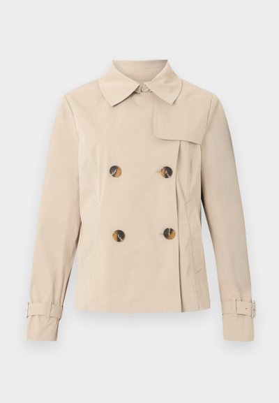 Trench-coat beige à double boutonnage avec large col, quatre boutons en écaille, poches latérales et sangles réglables avec boucles aux manches.