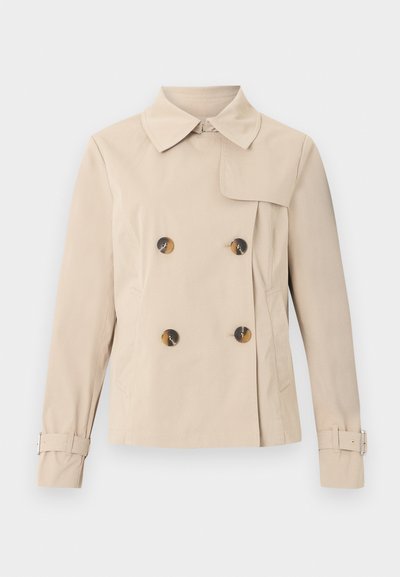 Trench-coat beige à double boutonnage avec large col, quatre boutons en écaille, poches latérales et sangles réglables avec boucles aux manches.