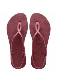 Infradito color mogano con suole in gomma texturizzata, cinturini intrecciati e un logo minimal. Presentano una forma elegante e arrotondata e un design moderno.