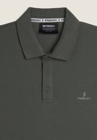 Polo shirt verde scuro realizzato in tessuto testurizzato, con colletto, tre bottoni e un piccolo logo stampato sul petto.