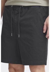 Mustad lühikesed püksid, mis on valmistatud kerge kangaga, varustatud elastse vöökohaga, millel on nöörid ja küljetaskud. Sile tekstuur, sirge lõige.