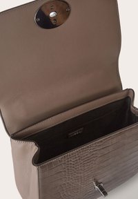 Bolso de mano de cuero con relieve de cocodrilo, color topo, con solapa redondeada y herrajes metálicos. El interior está forrado en tela negra.