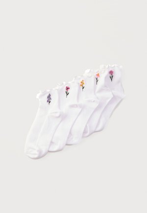 Ensemble de six chaussettes blanches à chevilles avec bords festonnés, chacune comportant une petite fleur brodée de différentes couleurs et styles près du revers.