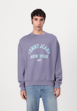 Paarse sweatshirt met geribbelde ronde hals. Bevat 'TOMMY JEANS NEW YORK CITY' in turquoise borduursel op de borst. Ruime pasvorm.