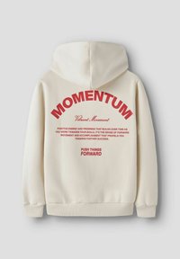 Krämfärgad hoodie med röd text på baksidan som säger "MOMENTUM" och motiverande fraser om framsteg och att gå framåt.