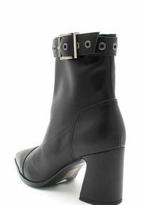 Czarny skórzany botek za kostkę z kwadratowym noskiem i szerokim blokowym obcasem. Posiada dekoracyjny pasek z oczkami i metalową klamrą.