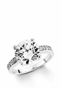 Silverring med stor rund diamanthuvudsten och mindre diamanter inbäddade längs bandet, mot en vit bakgrund.