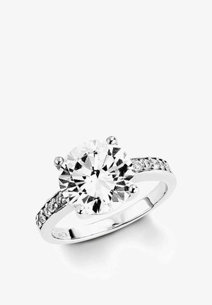 Bague en argent avec une grande pierre centrale ronde en diamant et de petits diamants incrustés le long de l'anneau, sur fond blanc.