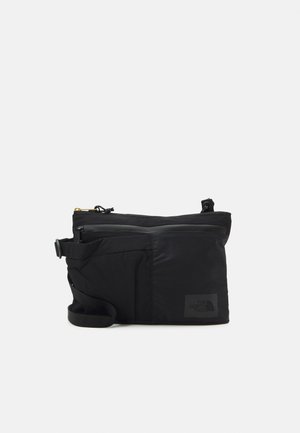 Schwarze rechteckige Crossbody-Tasche mit Reißverschlusstaschen und verstellbarem Riemen, mit einem dezenten North Face Logo auf der Vorderseite.