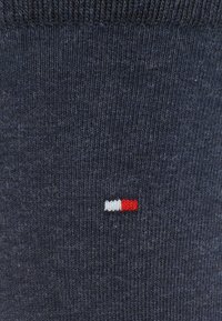 Calcetín de punto texturizado en azul marino con puño acanalado. Presenta un pequeño diseño de logotipo en tres colores en blanco, rojo y azul cerca del tobillo.