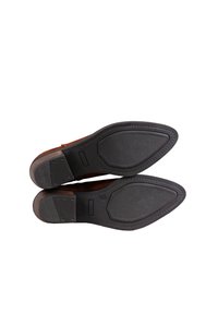 Zapatos de vestir de cuero marrón con un upper liso y una suela de goma que presenta una superficie texturizada, punta inclinada y mínimos detalles de costura.