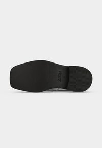 Semelle de chaussure noire avec des zones texturées au talon et à l'avant, avec le nom de la marque ZIGN et la taille 42 au centre.