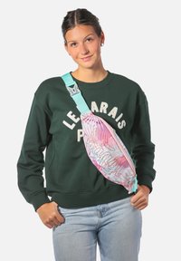 Marsupio multicolore con chiusura a zip, caratterizzato da un motivo tropicale in rosa e bianco, abbinato a una cintura larga turchese.