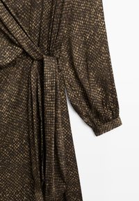 Langärmliges braunes Kleid mit einem kleinen beigen Punktmuster, das einen Taillengürtel und geknöpfte Ärmel hat.