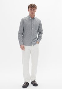 Grijs button-up shirt gemaakt van een gestructureerde stof, met een borstzak, gecombineerd met witte broek en zwarte schoenen met gesp-accenten.