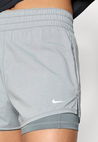 Γκρι αθλητικό σορτς από ελαφρύ ύφασμα, με ελαστική μέση και λευκό λογότυπο Nike. Διαθέτει λεία υφή με εσωτερική  επένδυση.